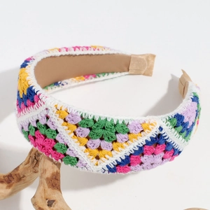 Detail of hand-crocheted wide headband featuring colorful patchwork squares and floral embroidery