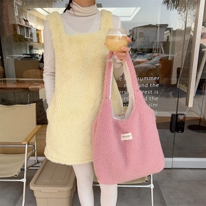 Detail of soft pink plush tote bag with white woven label and yellow fleece dress