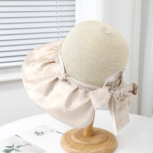 Elegante cappello da sole in paglia beige con grande fiocco e tesa in seta per l'estate