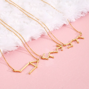 Three gold zodiac symbol necklaces with small crystals on a fine O-chain over pink background