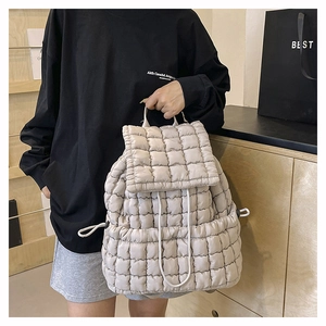 Dettaglio dello zaino trapuntato beige con trama imbottita e chiusura con coulisse