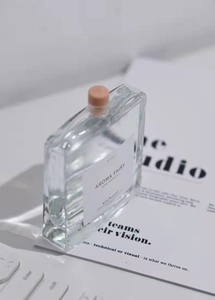 Primo piano della boccetta di profumo Aroma Fairy su una scrivania bianca minimalista