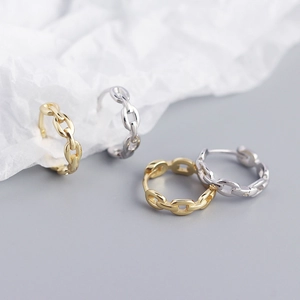 Detailed close-up of four gold and silver chain style earrings on aesthetic paper background