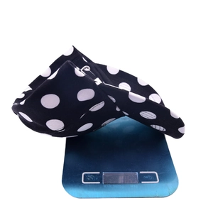 Lightweight polka dot baseball cap in black and white shown on a digital scale for weight measurement