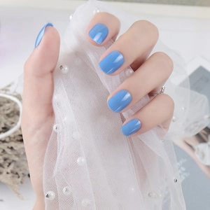 Close-up of glossy sky blue square oval press-on nails on elegant pearl lace background