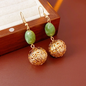 Detail of vintage resin round hollow pendant earrings with green beads and gold filigree