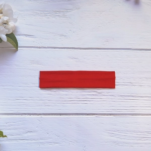 Détail du bandeau de yoga élastique rouge sur un fond de bois blanc rustique