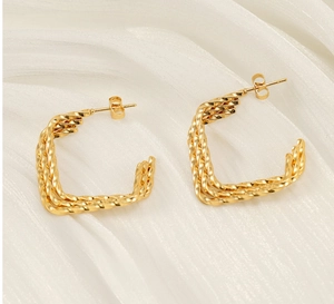 Gros plan de boucles d'oreilles torsadées en plaqué or 18 carats sur du tissu en soie