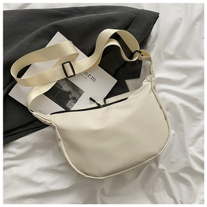 Detail shot of a cream crescent nylon bag with adjustable strap and zip closure