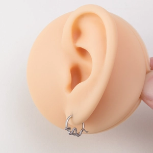 Polished stainless steel snake hoop earring worn on silicone ear model in silver finish