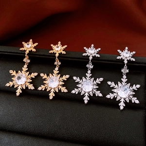Macro detail of snowflake earrings in gold and silver finish with sparkling cubic zirconia