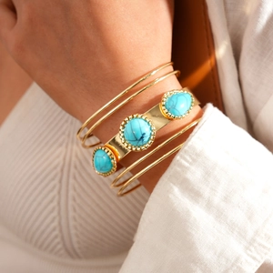 Close-up of bohemian gold bracelet set with turquoise stones on a knitted sleeve