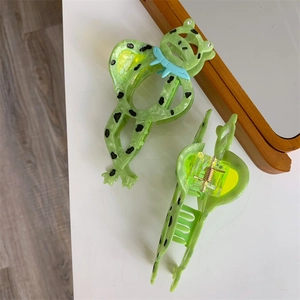 Nahaufnahme süßer grüner Frosch-Haarklammern mit schwarzen Punkten und blauen Schleifen