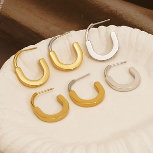 Minimalist U-shaped stainless steel hoop earrings in gold and silver set on a ceramic dish