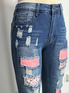 Dettaglio di jeans blu a vita alta con inserti in paillettes rosa e stampa leopardata