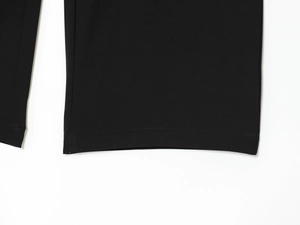Detailed close-up showing the double-stitched hem and fine woven texture of black trousers