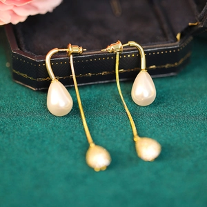 Detail of long pearl drop earrings with golden chains on a luxury jewelry box