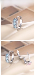 Detail view of silver earring with light blue zircons on champagne silk background