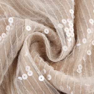 Detailed macro shot of elegant beige mesh fabric with dense white shimmering sequins