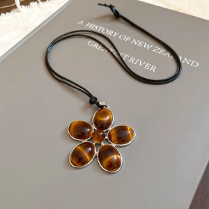 Detailed view of the vintage oval tiger eye flower pendant on a minimalist black cord