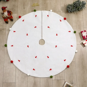 Jupe de sapin de Noël blanche avec broderies rouges et pompons sur sol en bois