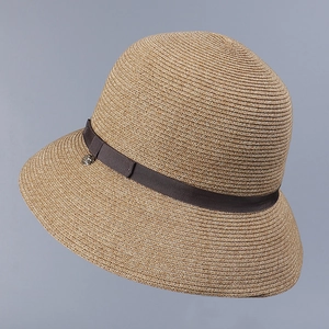 Close-up detail of a woven plant fiber sun hat in beige with dark brown ribbon band