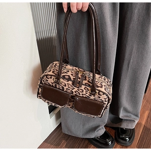 Close-up of leopard print handbag with leather pockets and gold zipper details