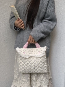Detail of the white quilted laptop sleeve with pink cotton handles and lace floral edges