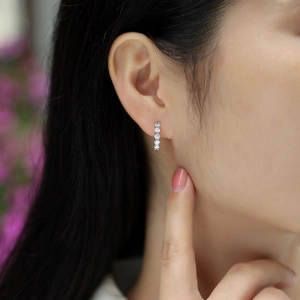 Detailed view of silver hoop earrings with double row moissanite on model's ear
