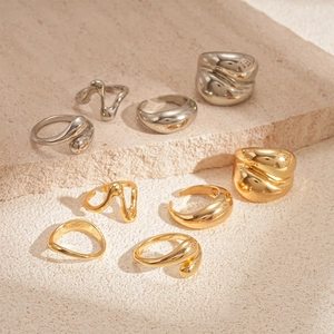 Minimale geometrische Tropfenringe in Gold und Silber auf Naturstein präsentiert