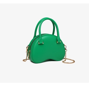 Detail of green PVC jelly bag featuring a half-moon design and gold chain shoulder strap