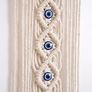 Handmade macrame wall hanging with three blue evil eye beads and decorative fringe