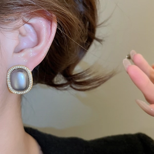 Detail of vintage oval gold earrings with cat eye stones worn by a model