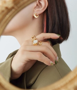 Detailed view of 18K gold-plated moon earrings and square ring with white sea shell inlay