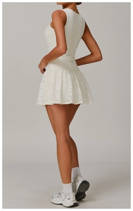 Detail of white lace sleeveless mini dress showing layered pleated hem and slim waistline