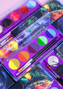 Flat lay of colorful UV neon face body paint kits with artistic brushes and packaging