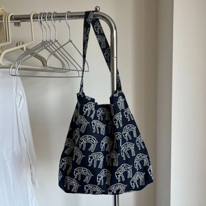 Detail of navy blue canvas tote bag featuring white animal embroidery and wide strap