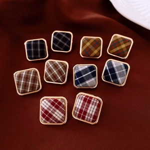 Vue détaillée de boucles d'oreilles carrées en tissu avec cadre doré et motifs écossais