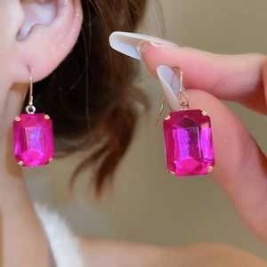 Close-up of elegant gold earrings featuring large rectangular pink gemstone fringe detail