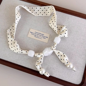 Detail of fabric pendant with polka dots, marble beads, and faux pearls on display