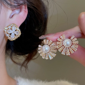 Detail of gold-plated stud earrings with sunburst zircon setting and round white pearl