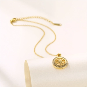 Gold starburst compass necklace with zircon accents on a soft beige roll background