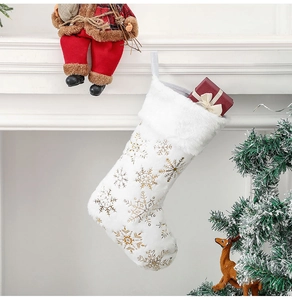 Détail d'une chaussette de Noël en peluche blanche avec des flocons dorés sur la cheminée
