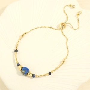 Detail of adjustable gold chain bracelet featuring blue sodalite beads and natural stone
