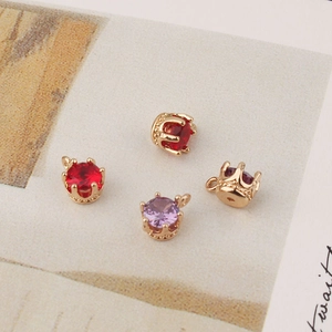 Detail showing red and purple crown pendants with gold plating for jewelry making