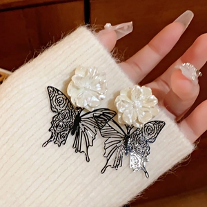 Close-up of retro butterfly earrings with white flower detail on a white knit sweater