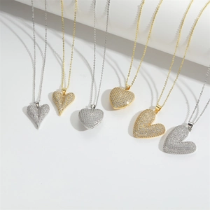 Elegant gold and silver heart necklaces with sparkling pavé crystals on white steps