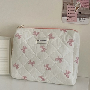 Dettaglio ravvicinato della borsa cosmetica trapuntata bianca con motivo a fiocchi