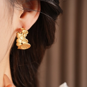 Gros plan détaillé des boucles d'oreilles dorées texturées en forme de C sur modèle