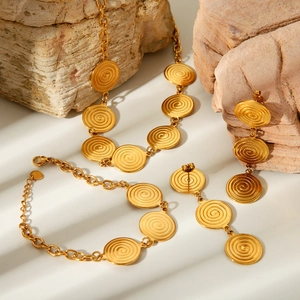 Detailed set of 18k gold plated spiral textured necklace bracelet and earrings on rock
